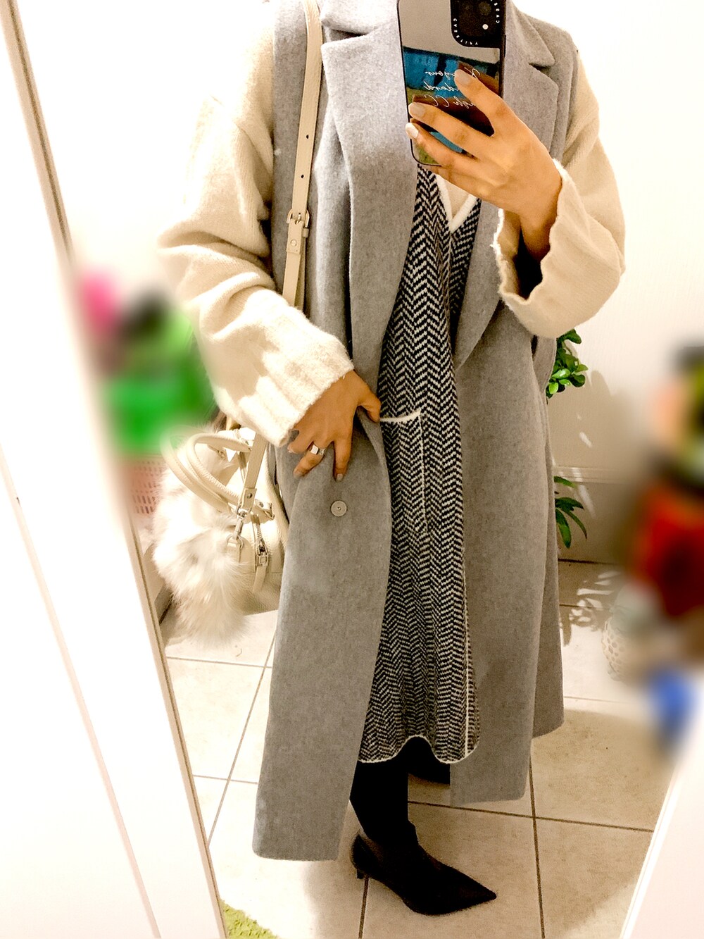 ホワイト系のショルダーバッグ、ホワイト系のニット/セーター、ブラック系のブーツを着用したレディースの冬コーディネートの2枚目の写真