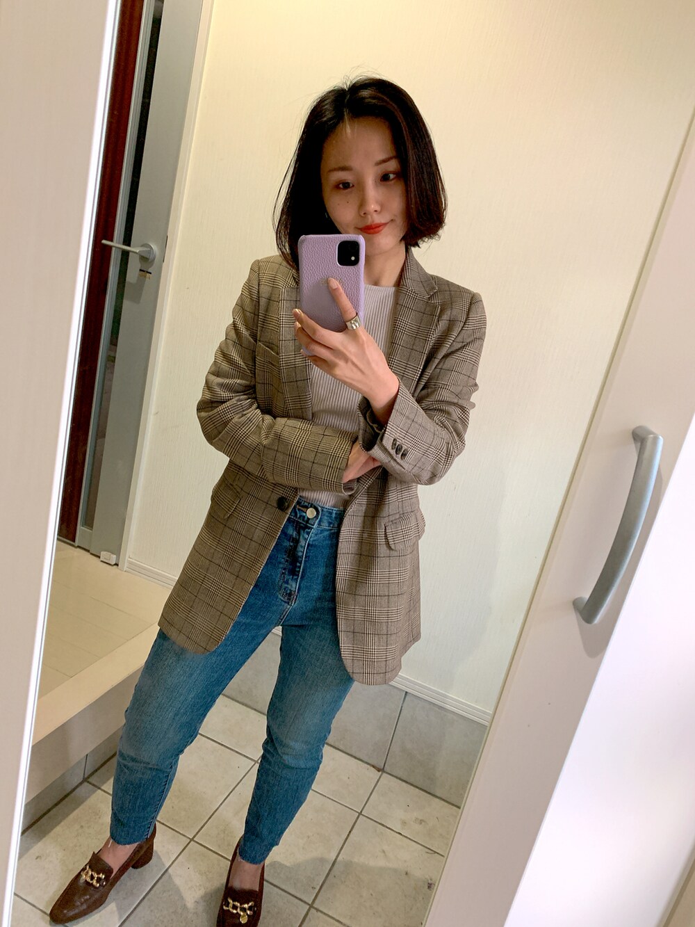 ブラウン系のテーラードジャケット、ブルー系のデニムパンツ、ブラウン系のパンプスを着用したレディースの秋コーディネートの2枚目の写真
