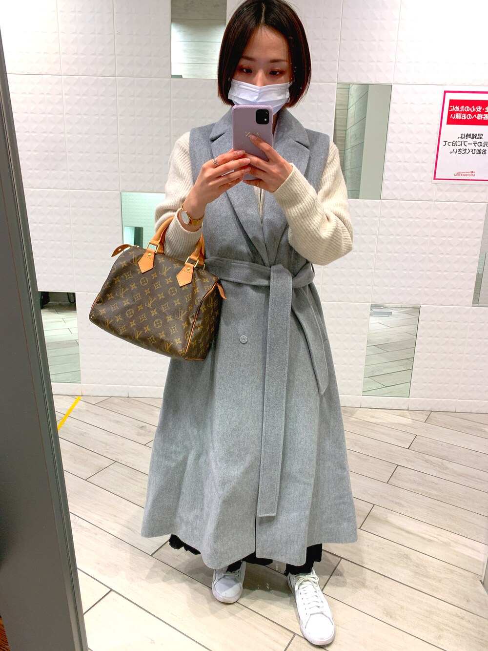 ブラウン系のボストンバッグ、グレー系のチェスターコート、ブラック系のスカートを着用したレディースの冬コーディネートの3枚目の写真