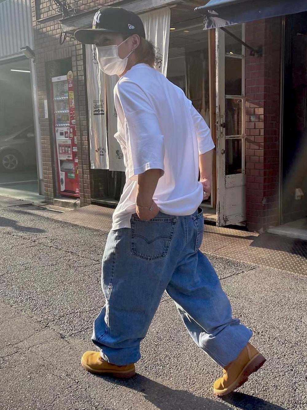 ホワイト系のTシャツ/カットソー、ブルー系のデニムパンツ、ベージュ系のブーツを着用したメンズの夏コーディネートの2枚目の写真