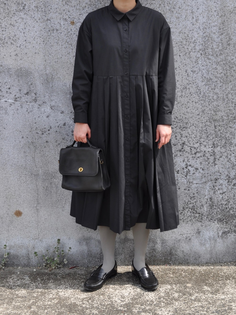 ブラック系のワンピース、ブラック系のパンプス、ブラック系のショルダーバッグを着用したレディースの春コーディネートの2枚目の写真