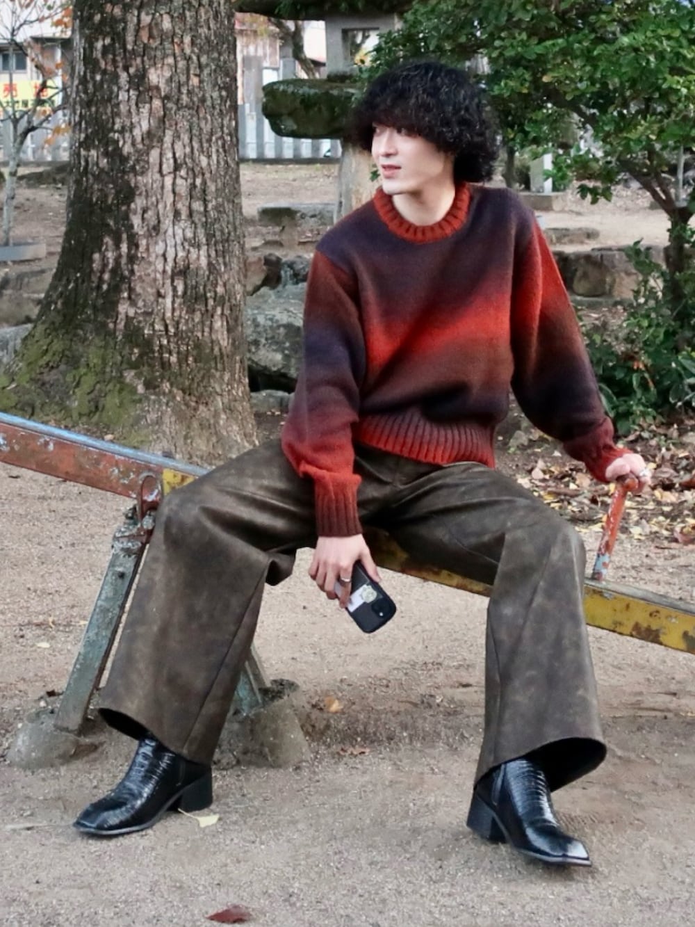 オレンジ系のニット/セーター、ブラウン系のその他パンツ、その他のブーツを着用したメンズの冬コーディネートの2枚目の写真