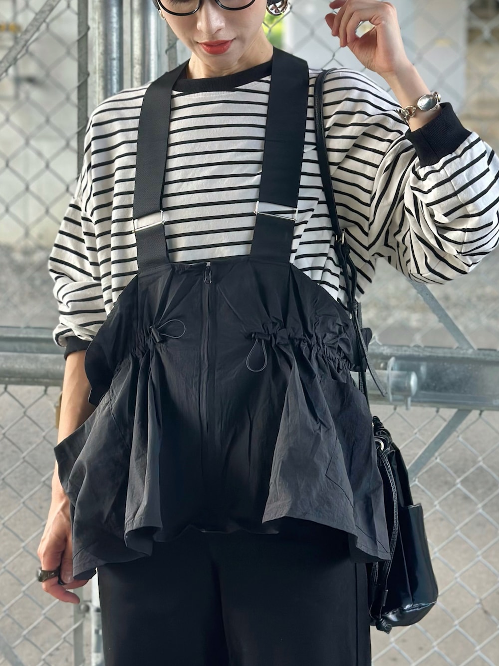 ブラック系のデニムパンツ、ベージュ系のスニーカー、ブラック系のTシャツ/カットソーを着用したレディースの秋コーディネートの2枚目の写真