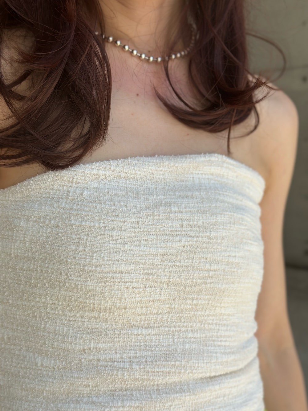 グレー系のテーラードジャケット、ホワイト系のチューブトップ、シルバー系のハンドバッグを着用したレディースの夏コーディネートの3枚目の写真