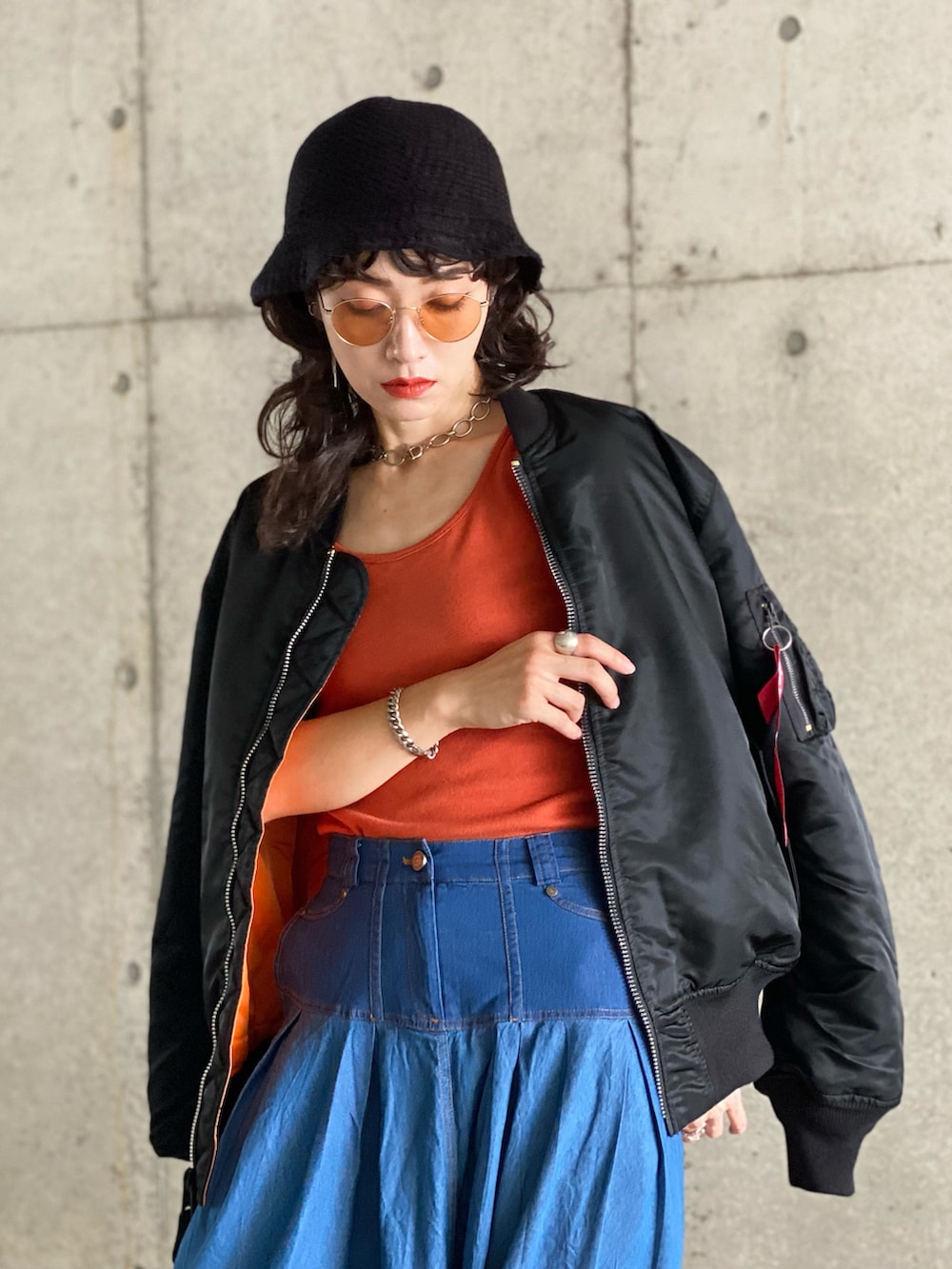 ブラック系のMA-1、ブルー系のデニムスカート、オレンジ系のタンクトップを着用したレディースの秋コーディネートの3枚目の写真