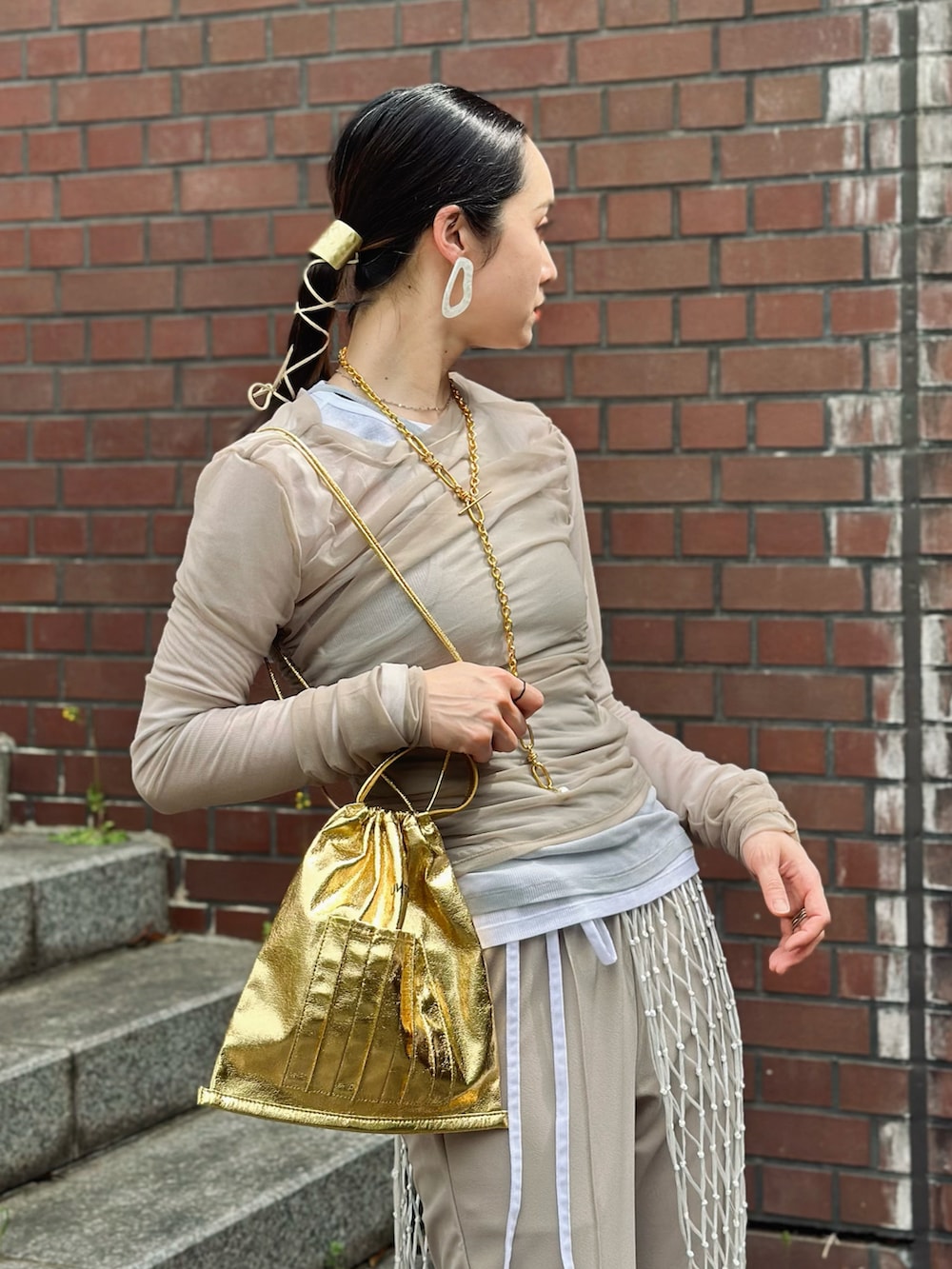 ベージュ系のその他パンツ、ベージュ系のTシャツ/カットソー、ゴールド系のショルダーバッグを着用したレディースの春コーディネートの2枚目の写真