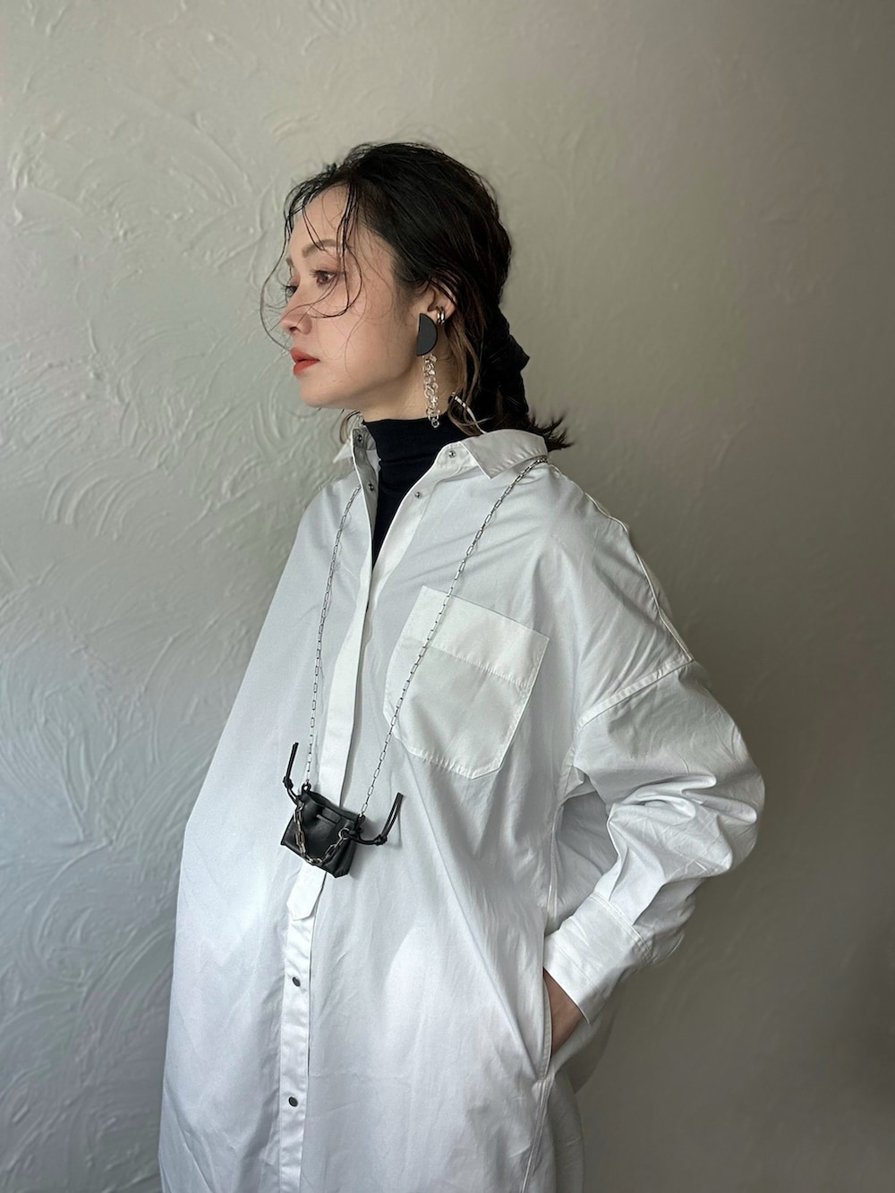 ホワイト系のシャツワンピース、ブラック系のショルダーバッグ、ブラック系のその他パンツを着用したレディースの冬コーディネートの2枚目の写真