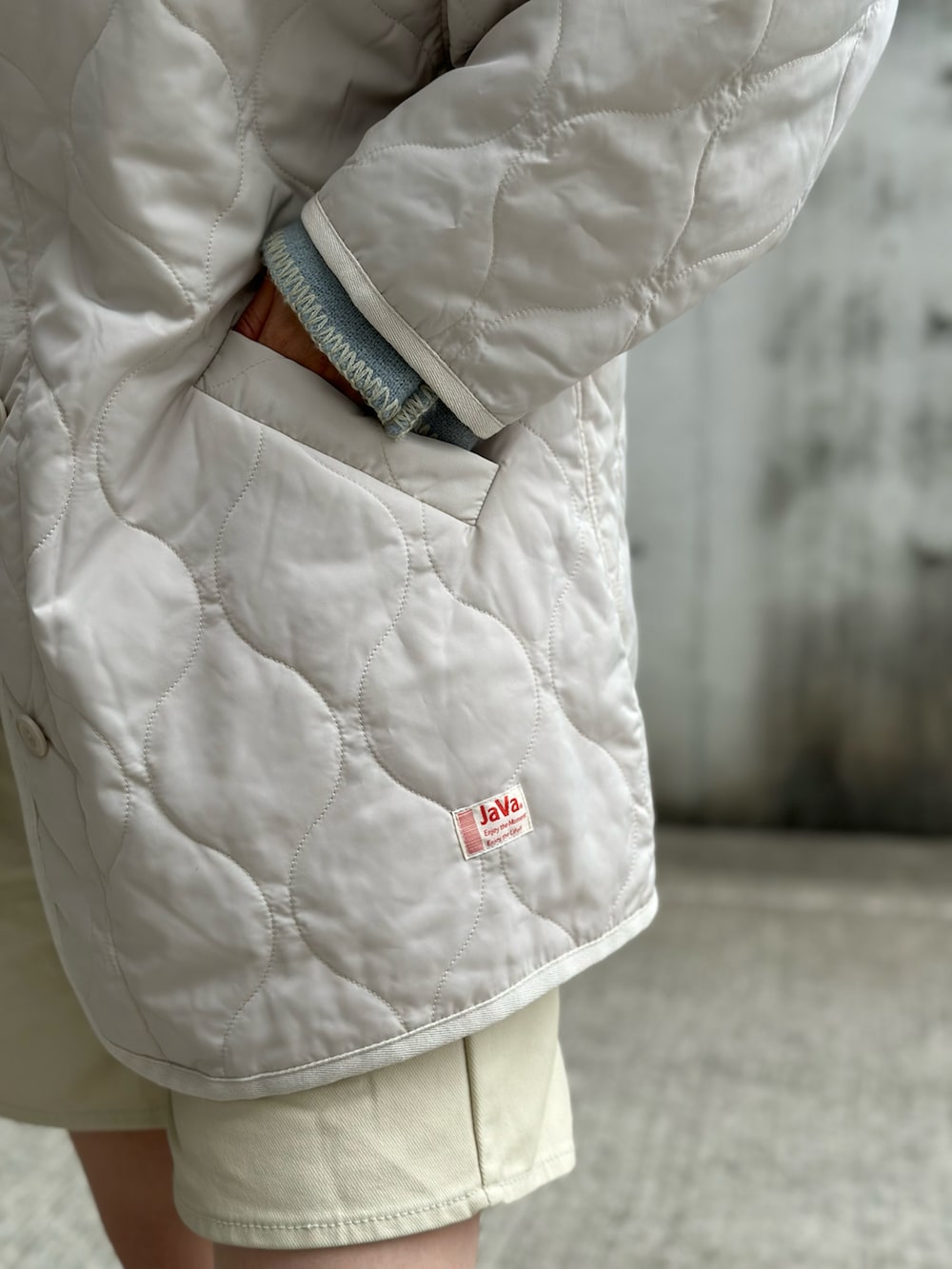 ホワイト系のノーカラージャケット、ブラウン系のベスト、ブルー系のニット/セーターを着用したレディースの冬コーディネートの4枚目の写真