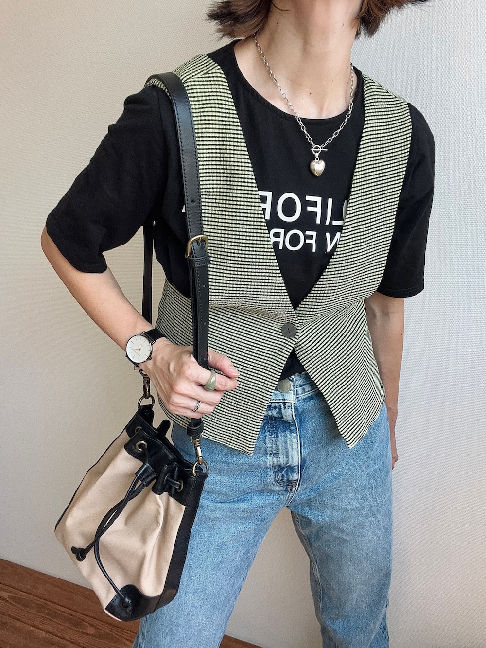 グリーン系のベスト、ブラック系のTシャツ/カットソー、ブルー系のデニムパンツを着用したレディースの夏コーディネートの2枚目の写真