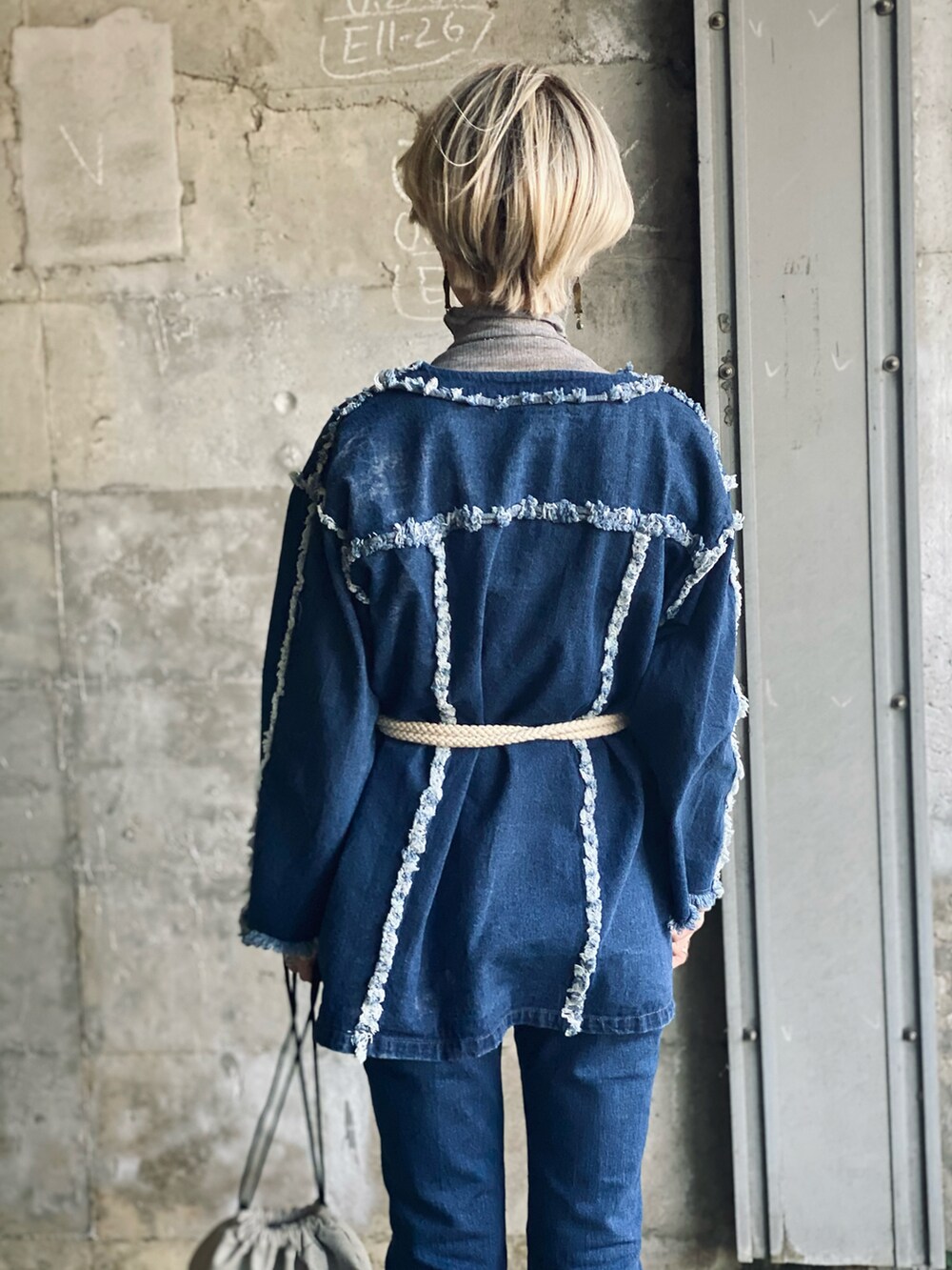 グレー系のTシャツ/カットソー、グレー系のトートバッグ、ブルー系のデニムジャケットを着用したレディースの冬コーディネートの2枚目の写真