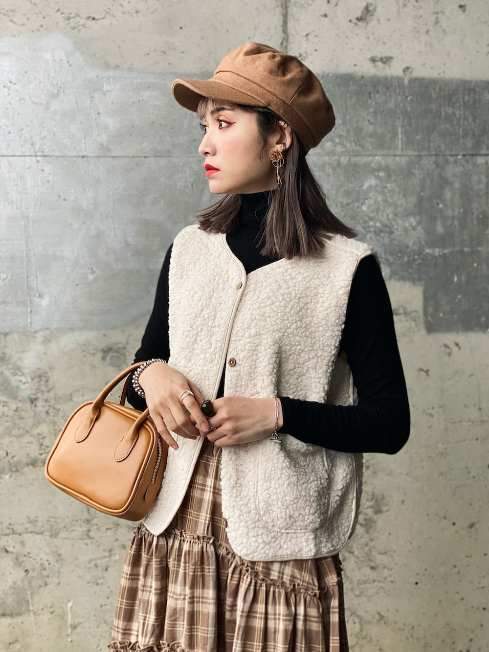 ブラウン系のスカート、ブラック系のTシャツ/カットソー、ブラウン系のブーツを着用したレディースの春コーディネートの2枚目の写真