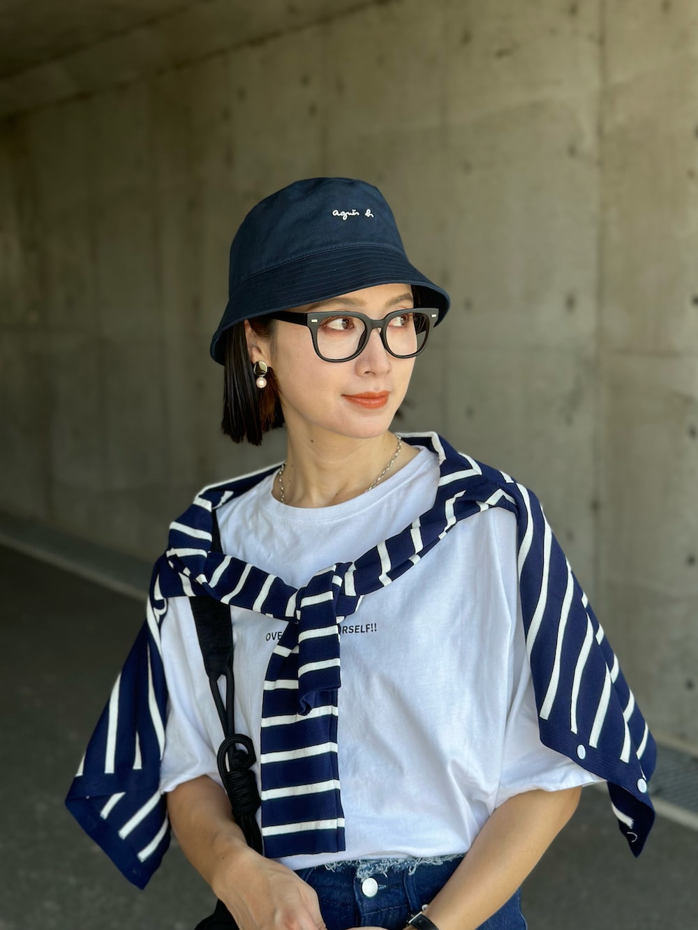 ブルー系のアンサンブル、ブラック系のショルダーバッグ、ブルー系のデニムパンツを着用したレディースの夏コーディネートの2枚目の写真