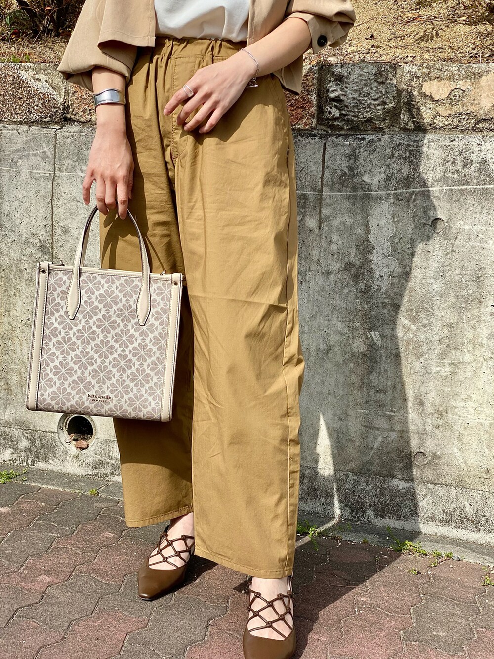 ブラック系のTシャツ/カットソー、ベージュ系のその他パンツ、ベージュ系のトレンチコートを着用したレディースの春コーディネートの5枚目の写真