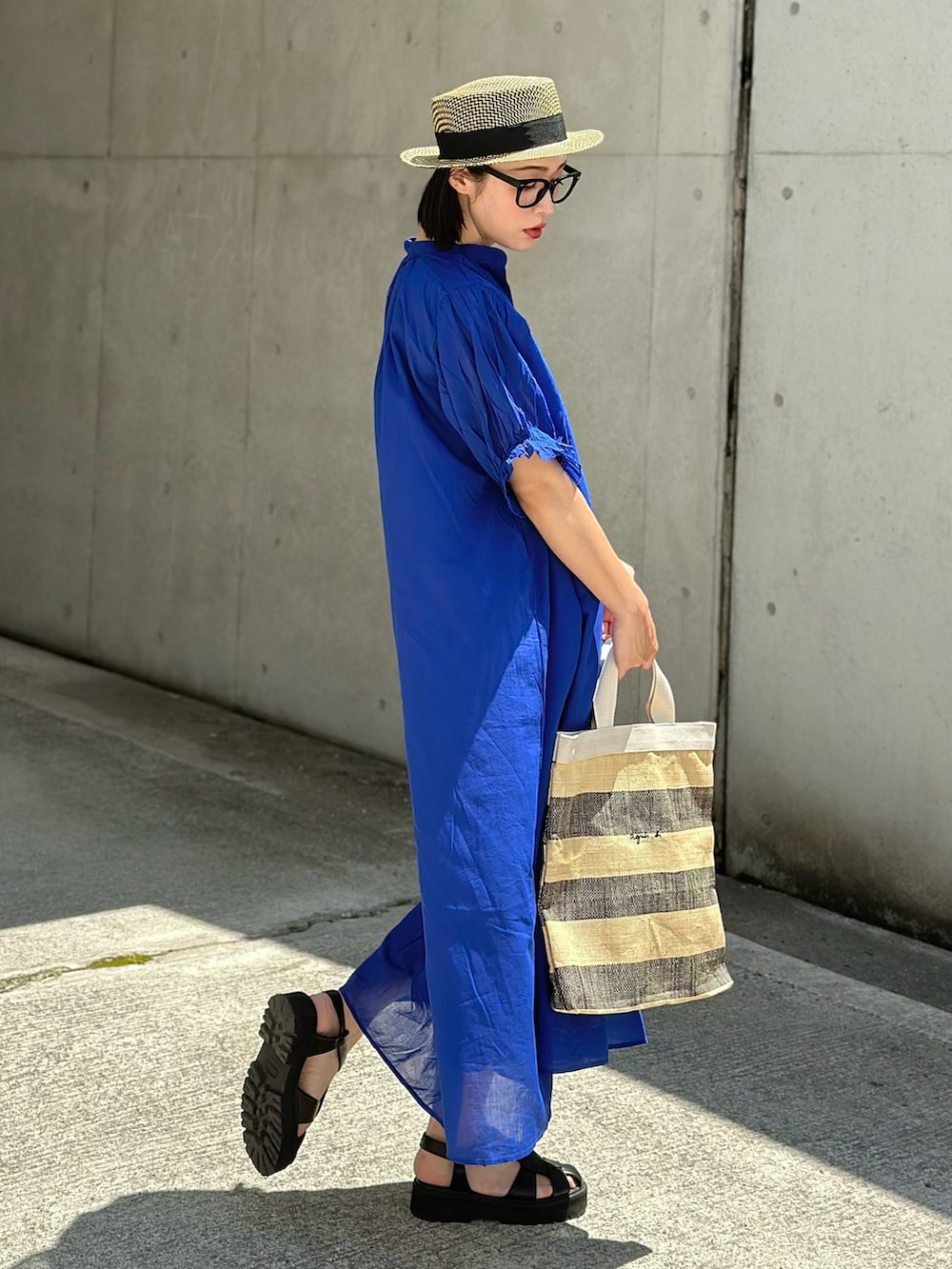 ブルー系のワンピース、ブラック系のトートバッグ、ブラック系のサンダルを着用したレディースの春コーディネートの5枚目の写真