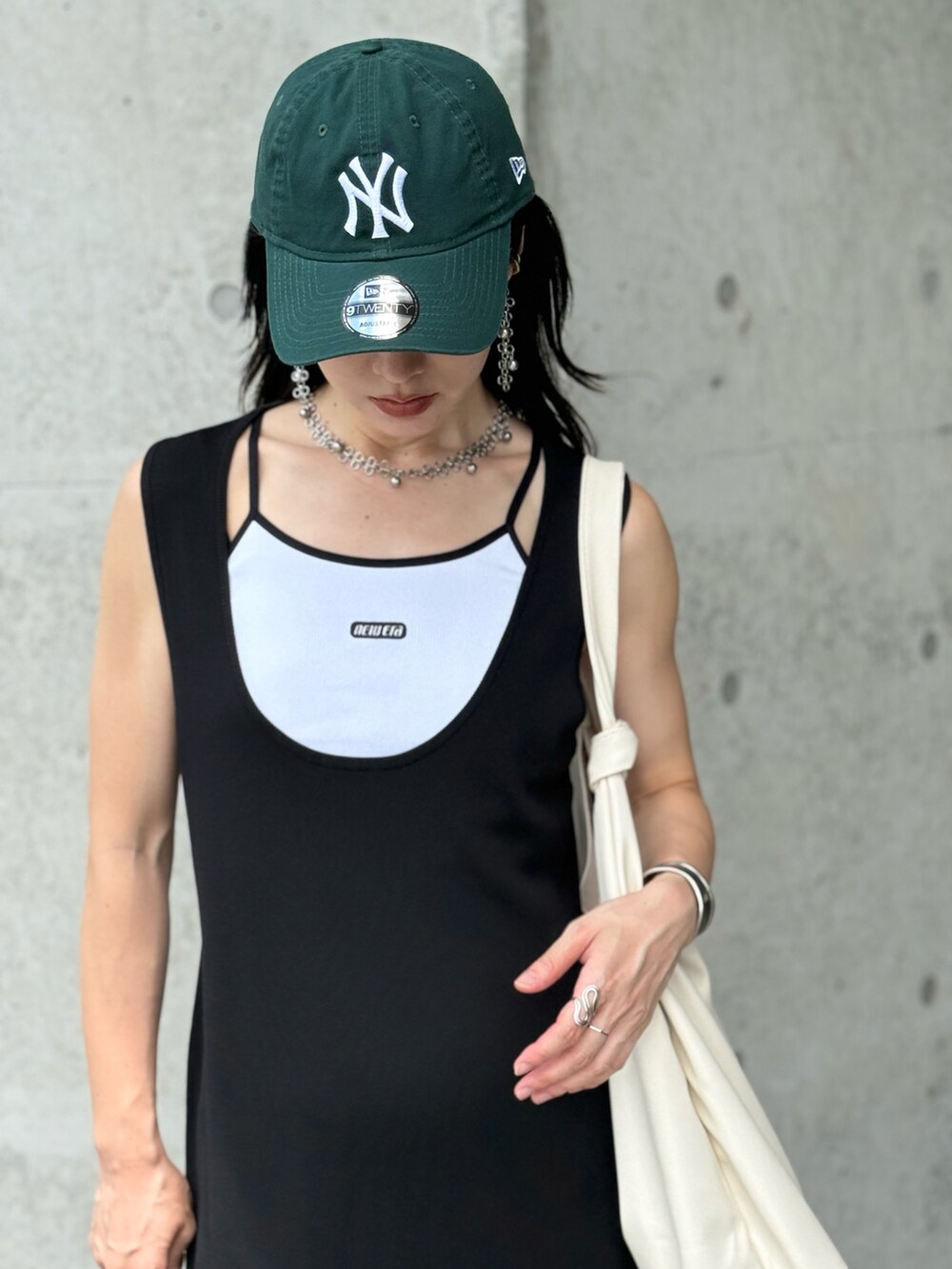 ホワイト系のキャミソール、ホワイト系のトートバッグ、ブラック系のワンピースを着用したレディースの夏コーディネートの2枚目の写真