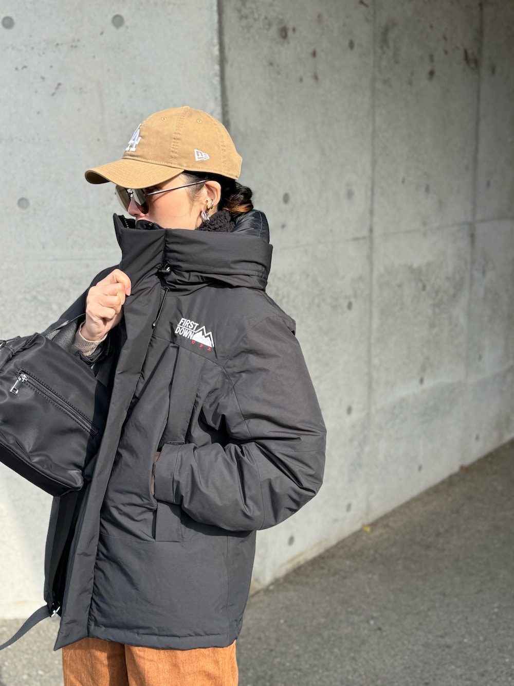 ブラック系のダウンジャケット/コート、ブラウン系のデニムパンツ、ブラック系のパンプスを着用したレディースの冬コーディネートの4枚目の写真