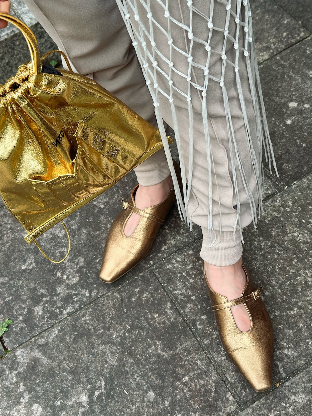 ベージュ系のその他パンツ、ベージュ系のTシャツ/カットソー、ゴールド系のショルダーバッグを着用したレディースの春コーディネートの5枚目の写真