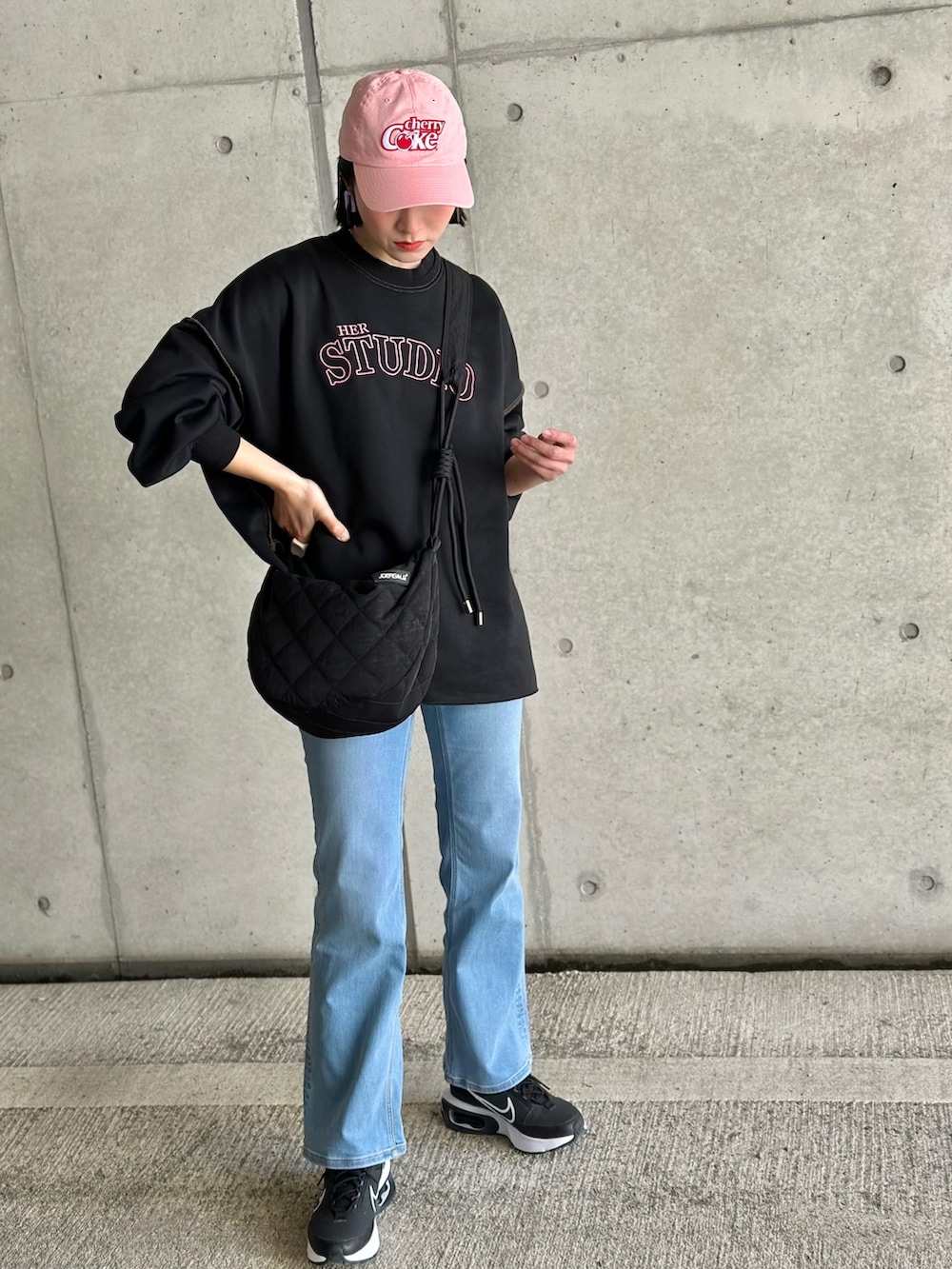 ブルー系のデニムパンツ、ブラック系のショルダーバッグ、ブラック系のスウェットを着用したレディースの春コーディネートの4枚目の写真