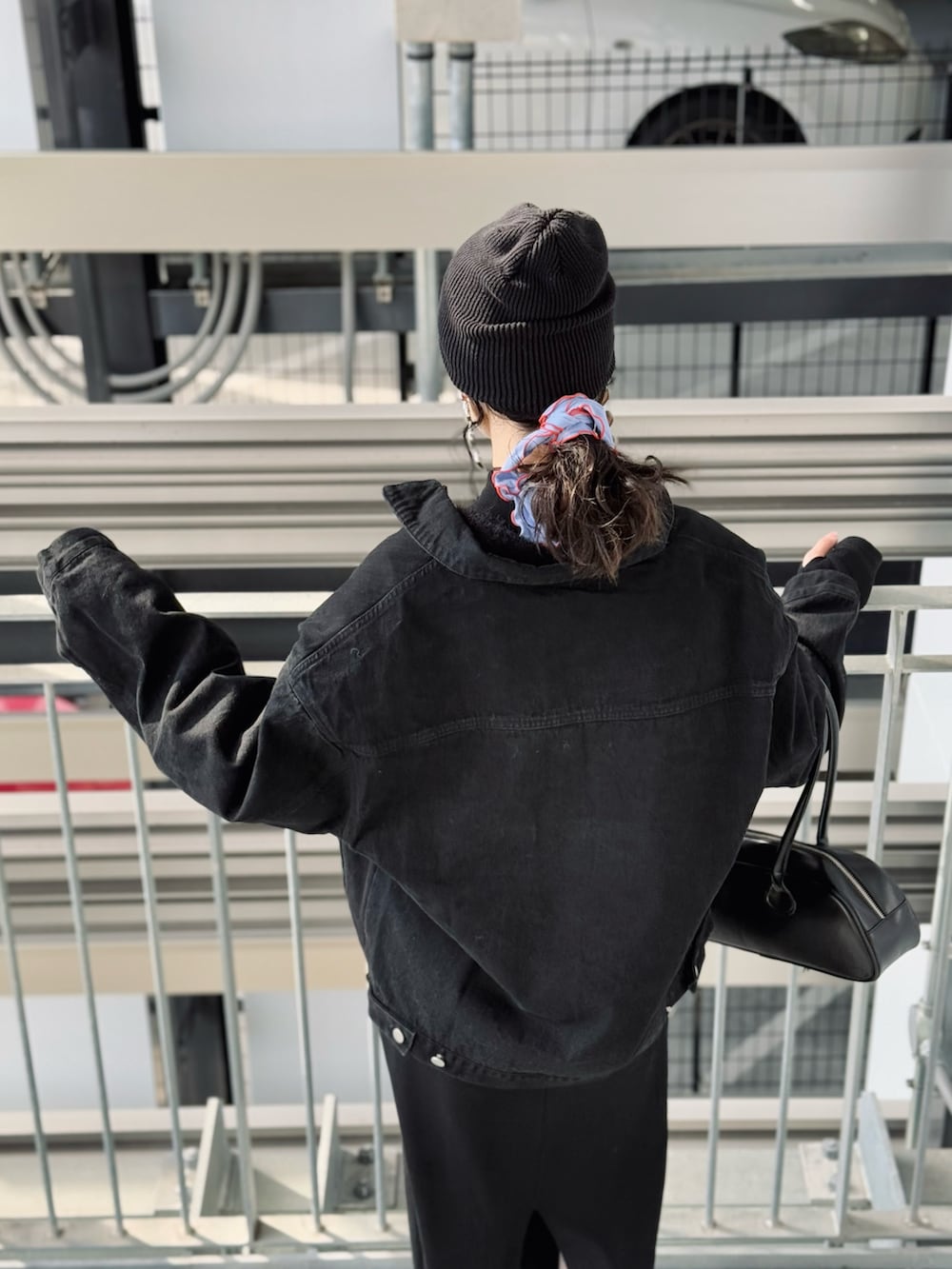 ブラック系のデニムジャケット、ブラック系のワンピース、ブラック系のボストンバッグを着用したレディースの冬コーディネートの3枚目の写真