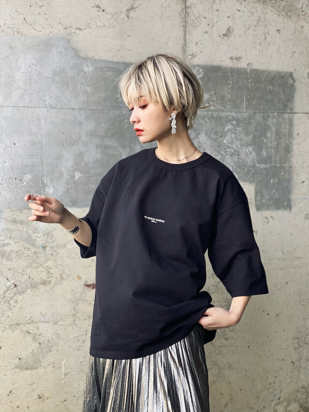 シルバー系のスカート、ブラック系のブーツ、ブラック系のTシャツ/カットソーを着用したレディースの春コーディネートの3枚目の写真