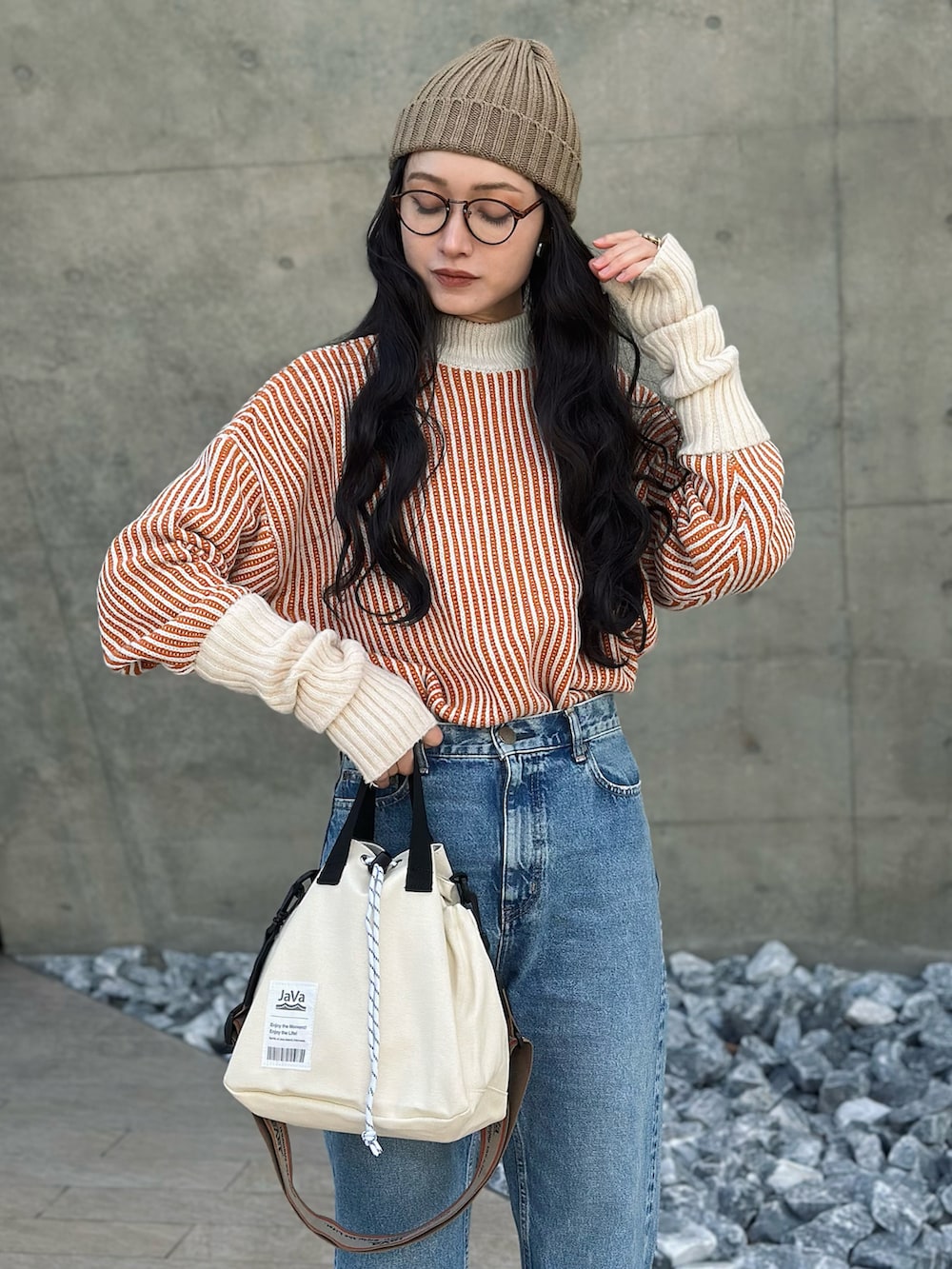 ベージュ系のブルゾン、オレンジ系のニット/セーター、ホワイト系のショルダーバッグを着用したレディースの冬コーディネートの2枚目の写真