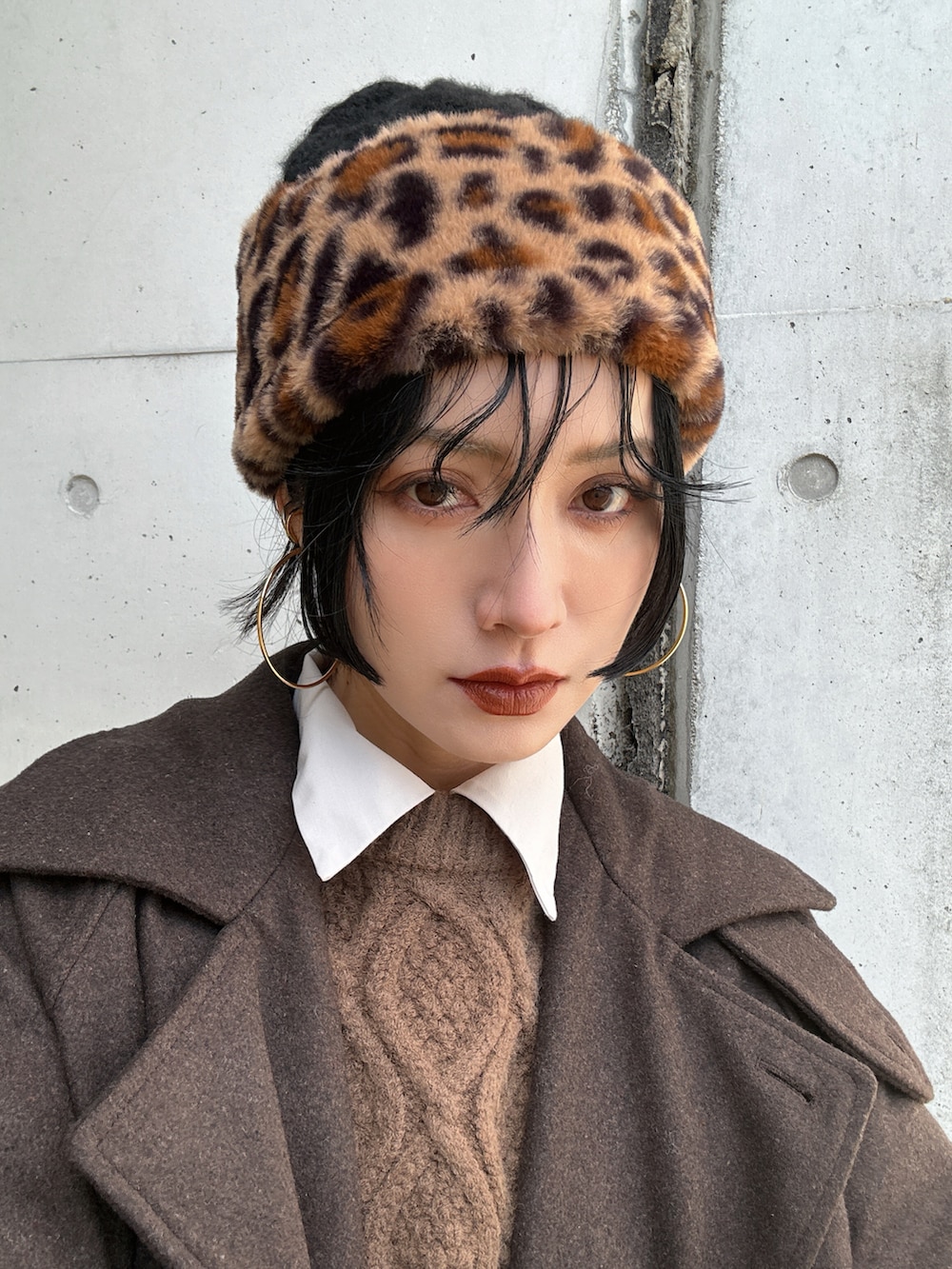 ブラウン系のステンカラーコート、ブラック系のハンドバッグ、ブラック系のその他パンツを着用したレディースの冬コーディネートの4枚目の写真