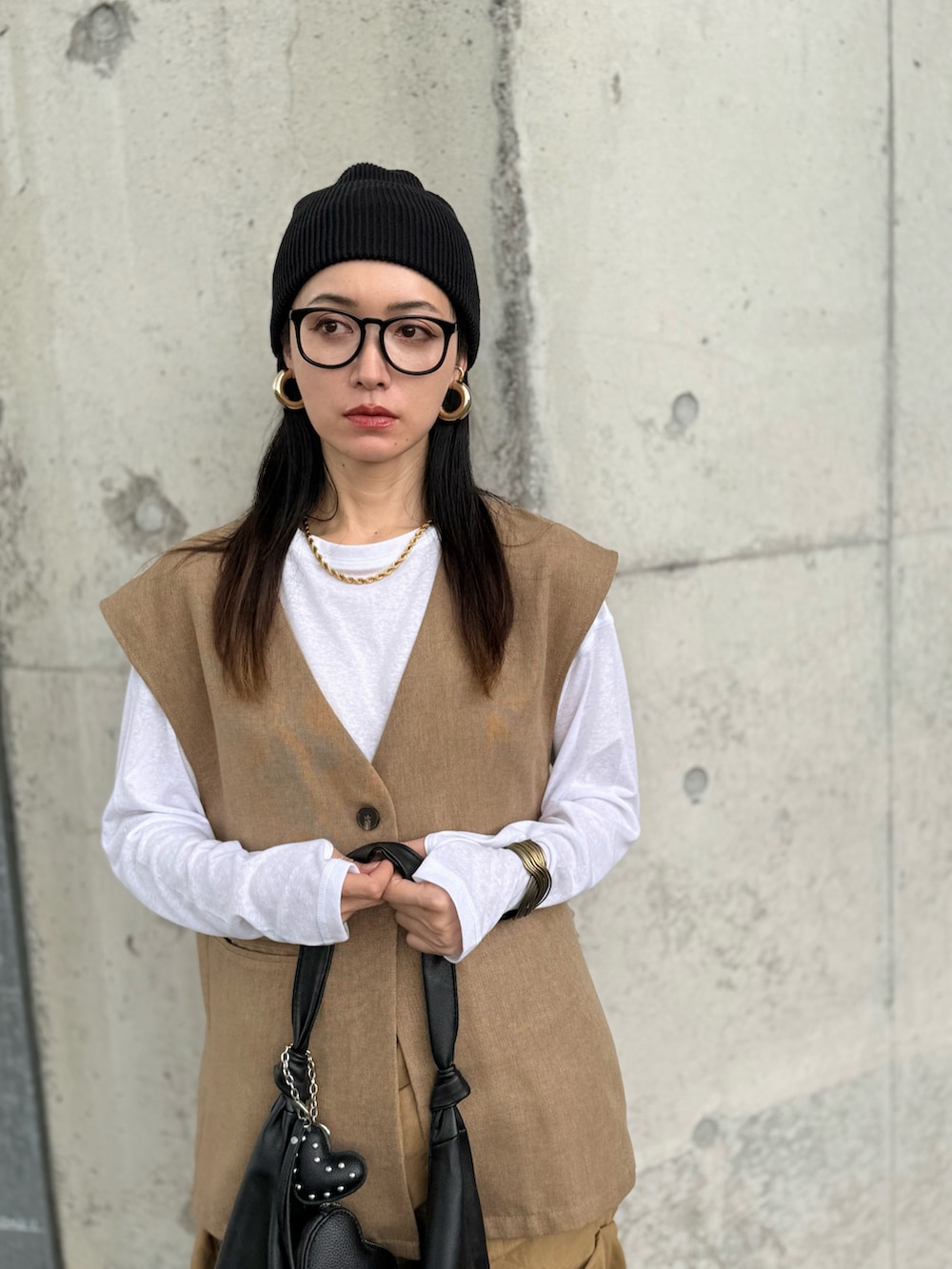 グリーン系のベスト、ホワイト系のTシャツ/カットソー、ベージュ系のスカートを着用したレディースの秋コーディネートの2枚目の写真