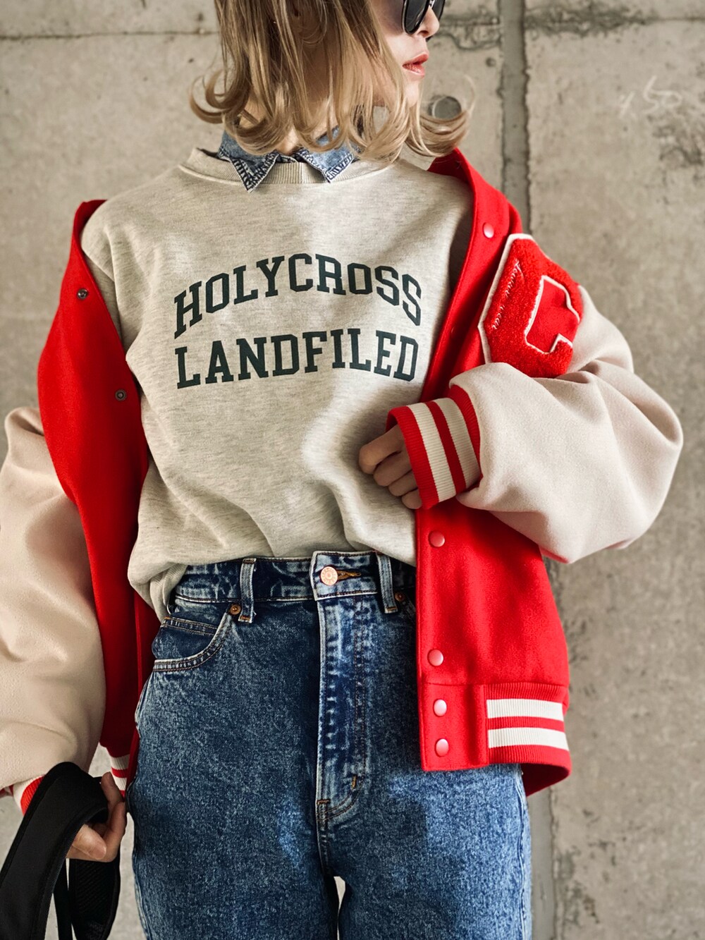 レッド系のスタジャン、ベージュ系のスウェット、ブルー系のデニムパンツを着用したレディースの冬コーディネートの5枚目の写真