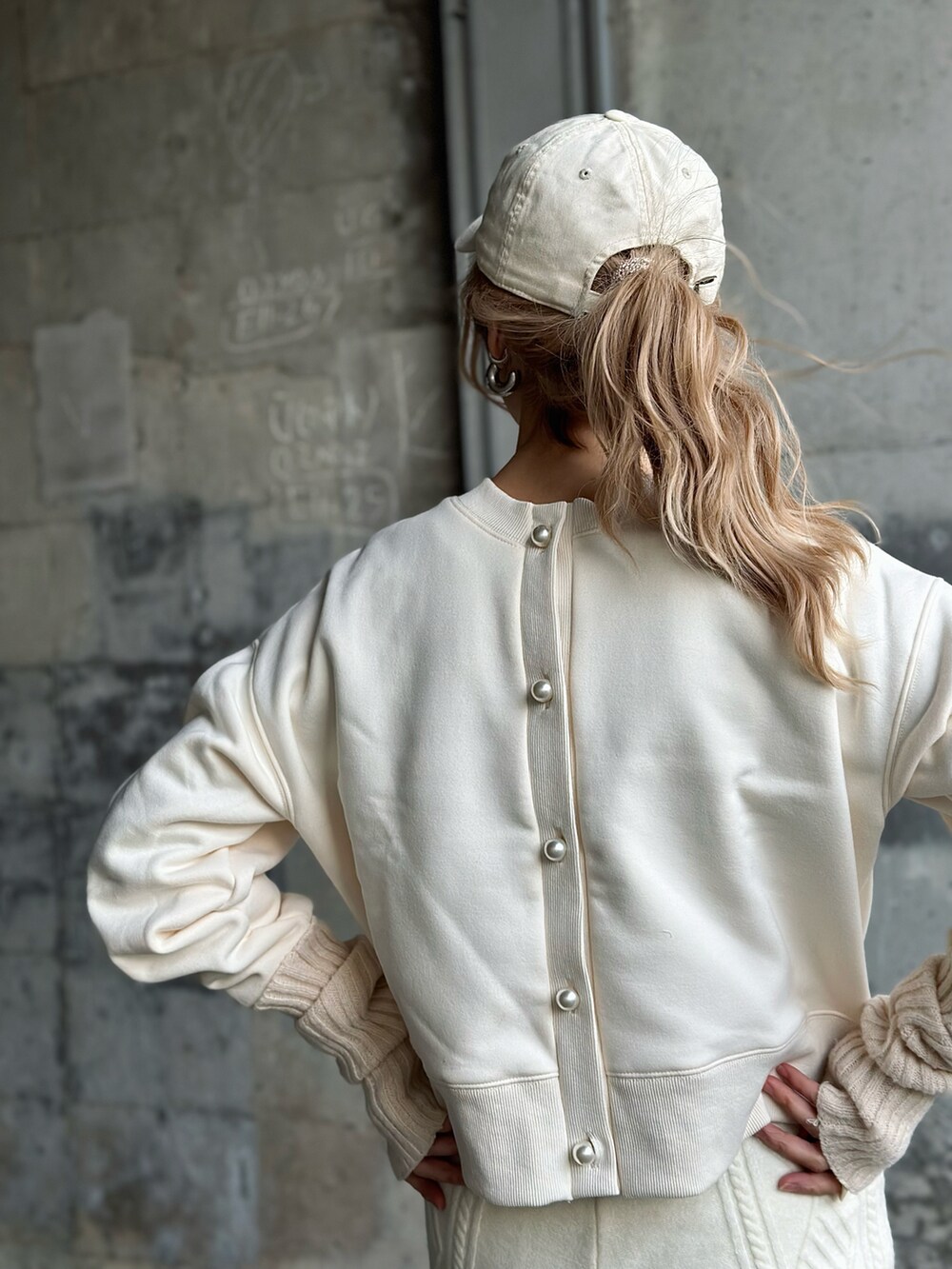 ホワイト系のスウェット、ベージュ系のダウンベスト、ホワイト系のスニーカーを着用したレディースの冬コーディネートの4枚目の写真