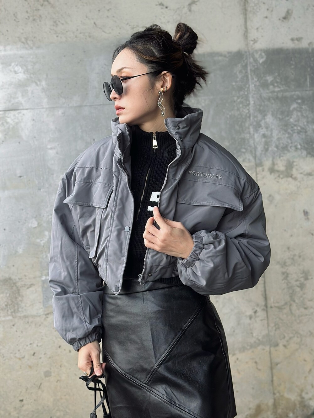 ブラック系のハンドバッグ、シルバー系のブーツ、グレー系のブルゾンを着用したレディースの冬コーディネートの2枚目の写真