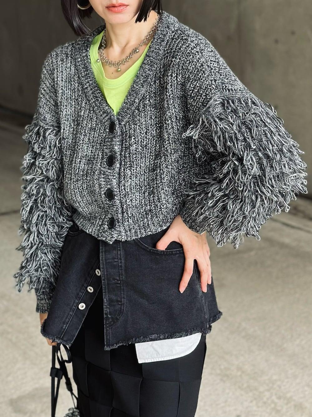 ブラック系のブーツ、ブラック系のカーディガン/ボレロ、シルバー系のハンドバッグを着用したレディースの秋コーディネートの3枚目の写真