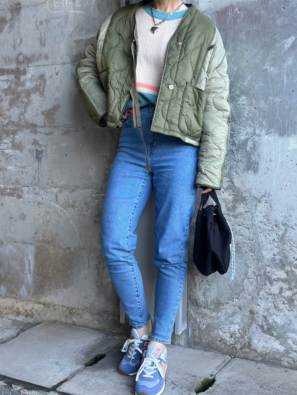 ホワイト系のニット/セーター、ブルー系のデニムパンツ、グリーン系のミリタリージャケットを着用したレディースの冬コーディネートの2枚目の写真