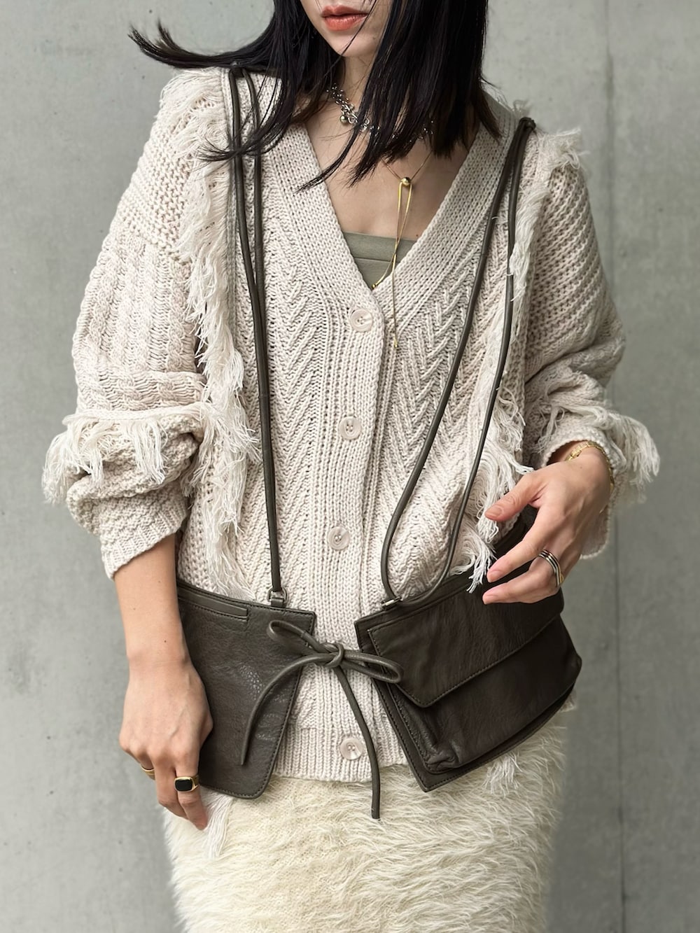 ホワイト系のスカート、ゴールド系のショルダーバッグ、グリーン系のボディバッグ/ウエストポーチを着用したレディースの秋コーディネートの2枚目の写真