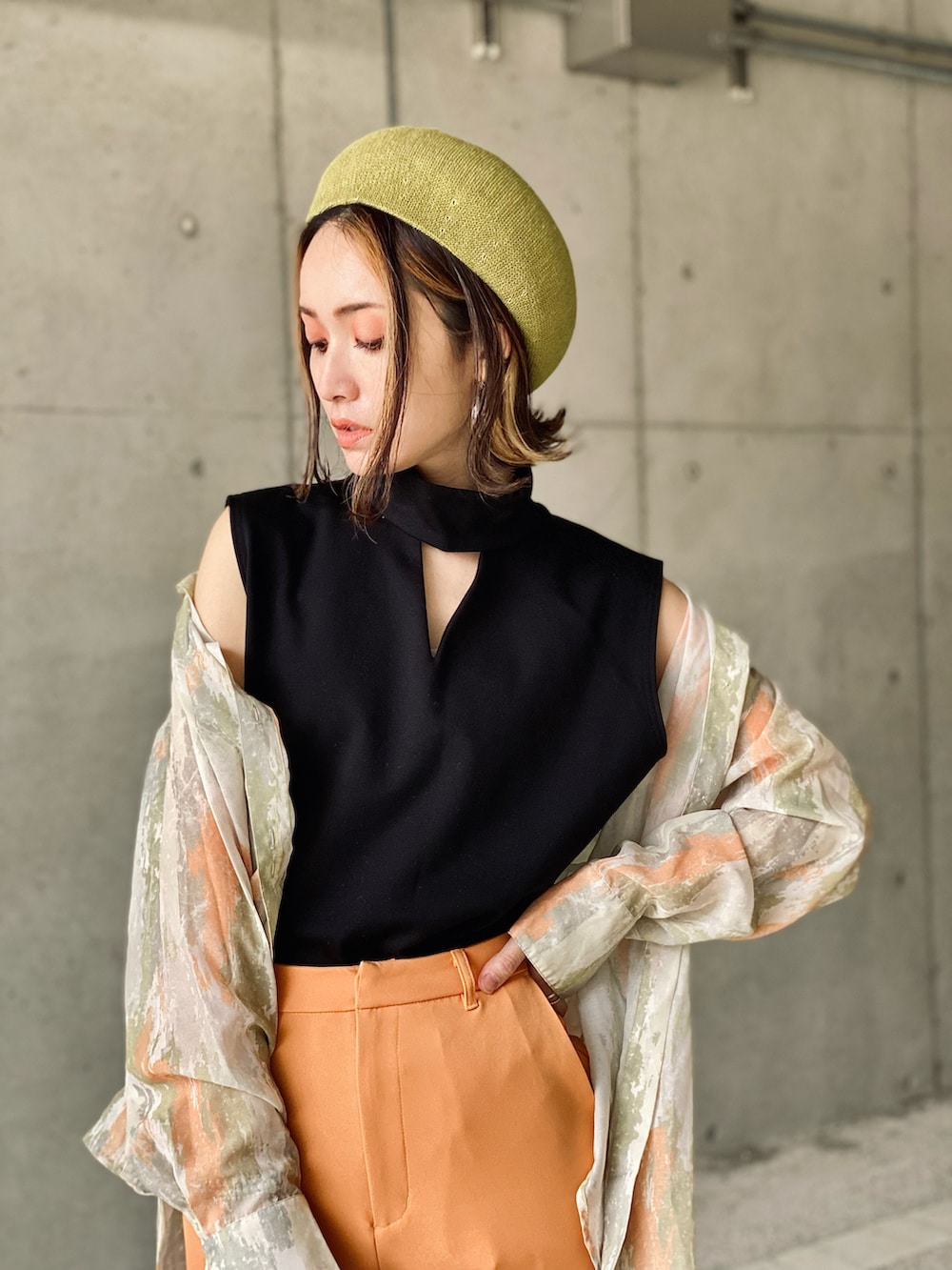 ブラック系のTシャツ/カットソー、オレンジ系のスラックス、グリーン系のハンドバッグを着用したレディースの春コーディネートの2枚目の写真