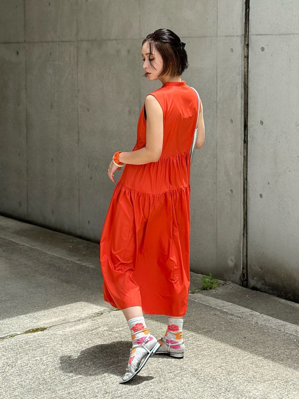 オレンジ系のワンピース、シルバー系のショルダーバッグ、シルバー系のサンダルを着用したレディースの春コーディネートの4枚目の写真