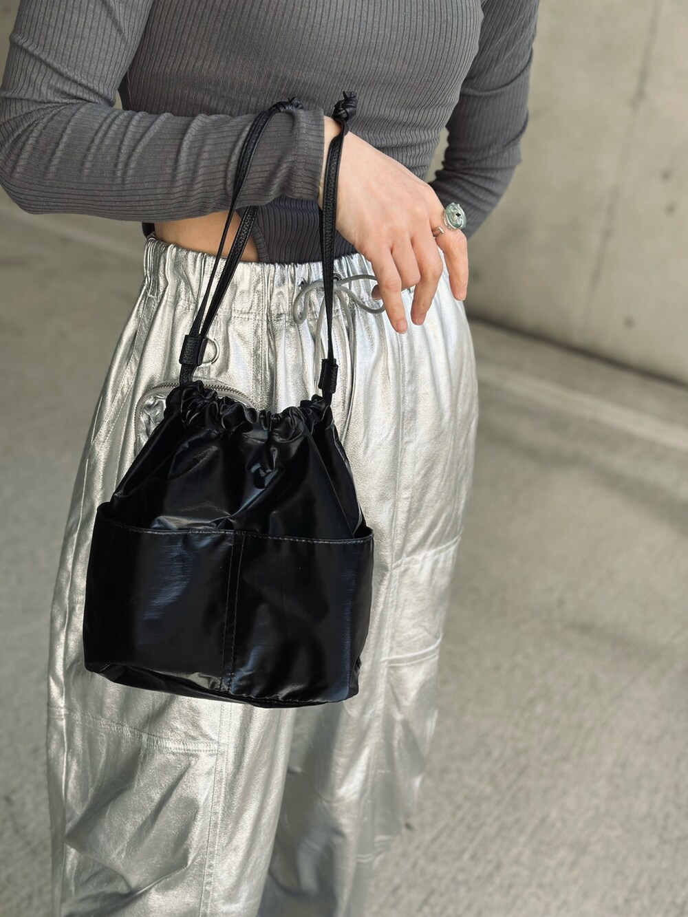 ブラック系のハンドバッグ、シルバー系のその他パンツ、ブルー系のチェスターコートを着用したレディースの冬コーディネートの4枚目の写真