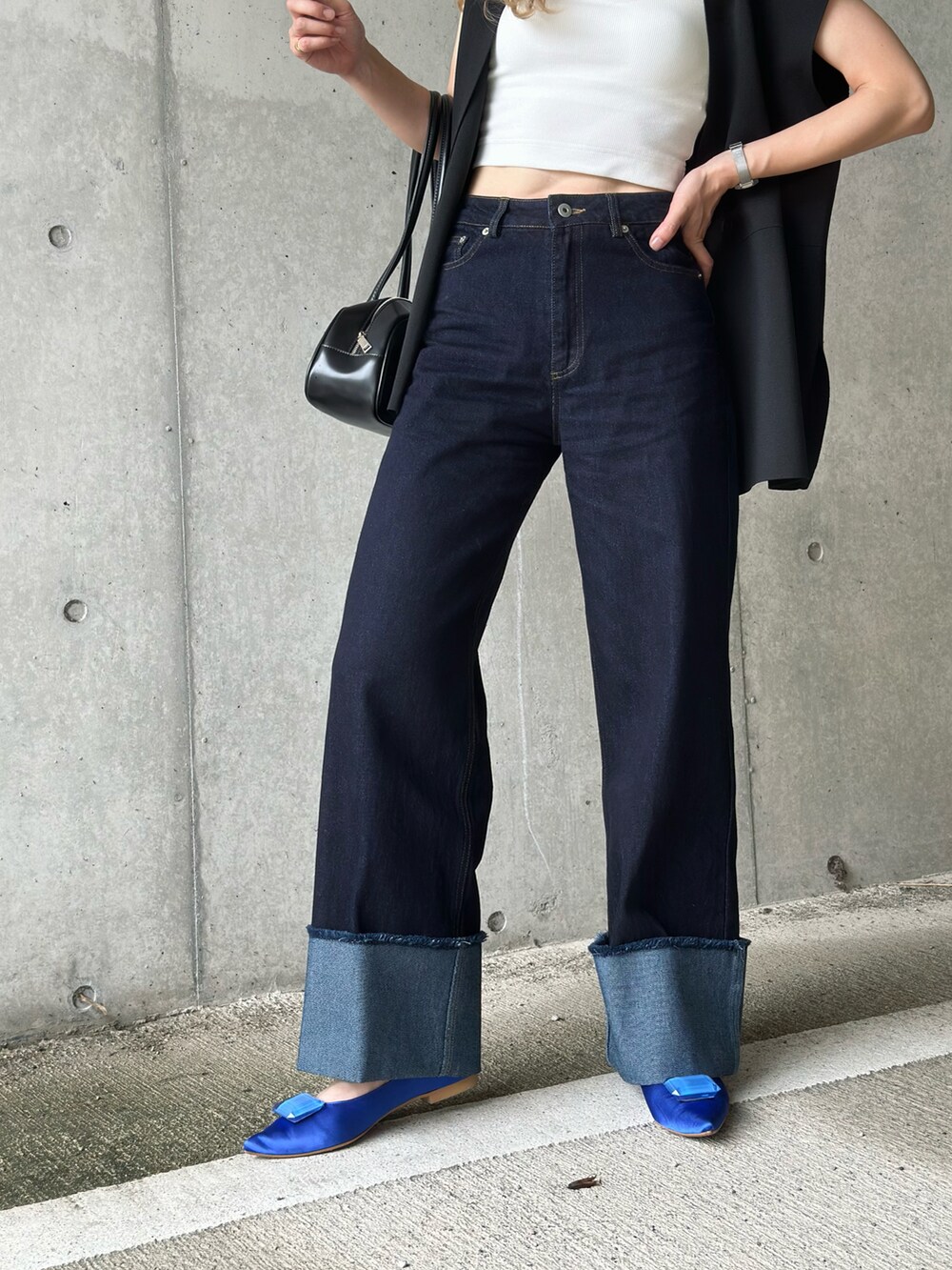 ブルー系のデニムパンツ、ホワイト系のキャミソール、ブルー系のパンプスを着用したレディースの夏コーディネートの2枚目の写真