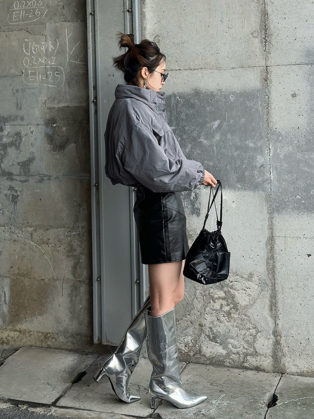 ブラック系のハンドバッグ、シルバー系のブーツ、グレー系のブルゾンを着用したレディースの冬コーディネートの3枚目の写真