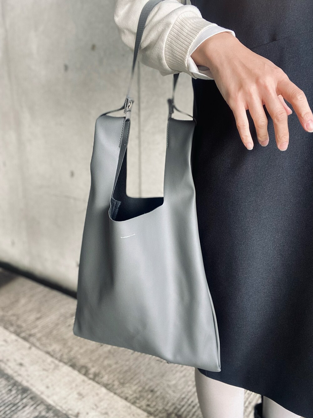 ホワイト系のブルゾン、ブラック系のワンピース、グレー系のショルダーバッグを着用したレディースの冬コーディネートの3枚目の写真