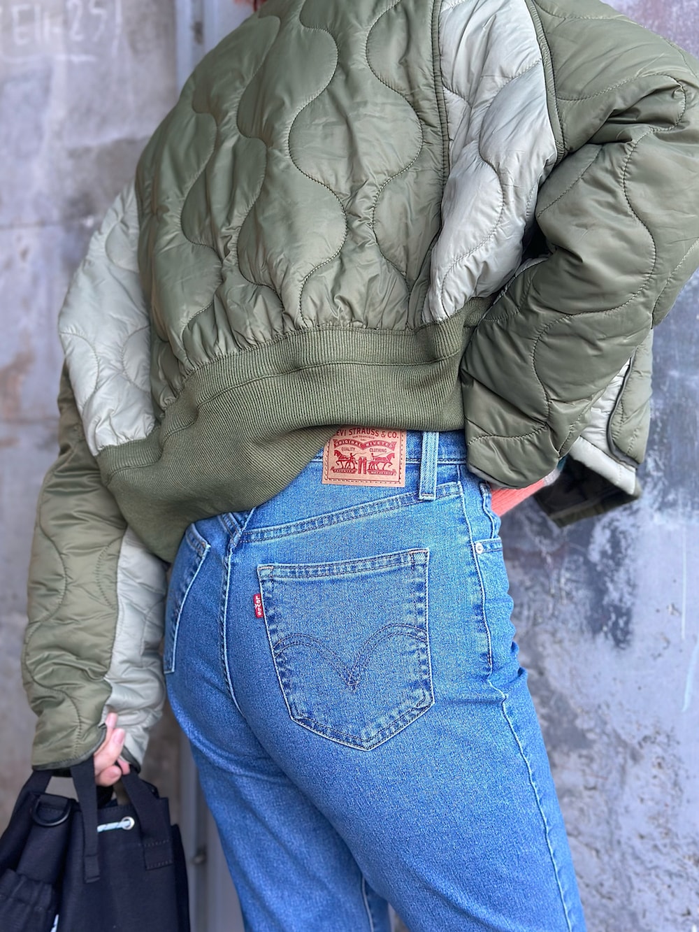 ホワイト系のニット/セーター、ブルー系のデニムパンツ、グリーン系のミリタリージャケットを着用したレディースの冬コーディネートの5枚目の写真