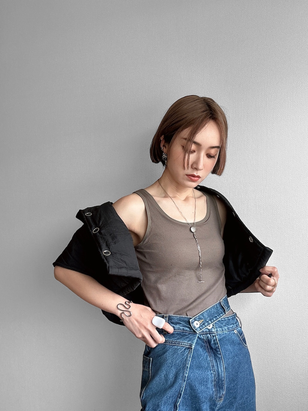 グリーン系のタンクトップ、ブルー系のデニムパンツ、ブラック系のその他アウターを着用したレディースの春コーディネートの5枚目の写真