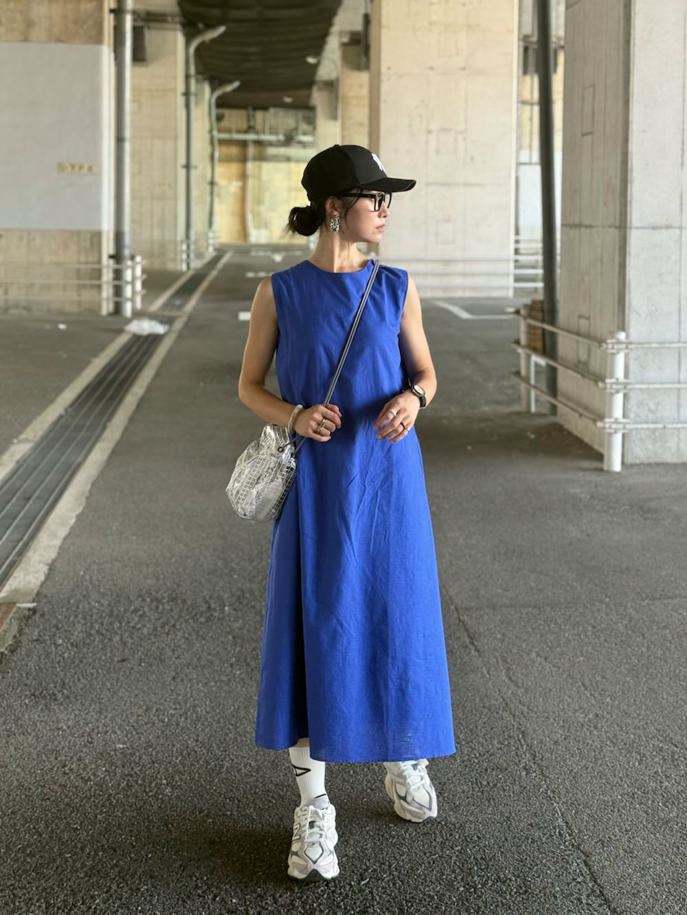 ブルー系のワンピース、ベージュ系のスニーカー、ブラック系のキャップを着用したレディースの夏コーディネートの3枚目の写真