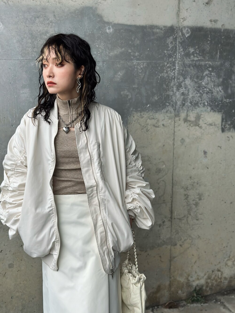 ホワイト系のスカート、ホワイト系のMA-1、ベージュ系のニット/セーターを着用したレディースの冬コーディネートの3枚目の写真