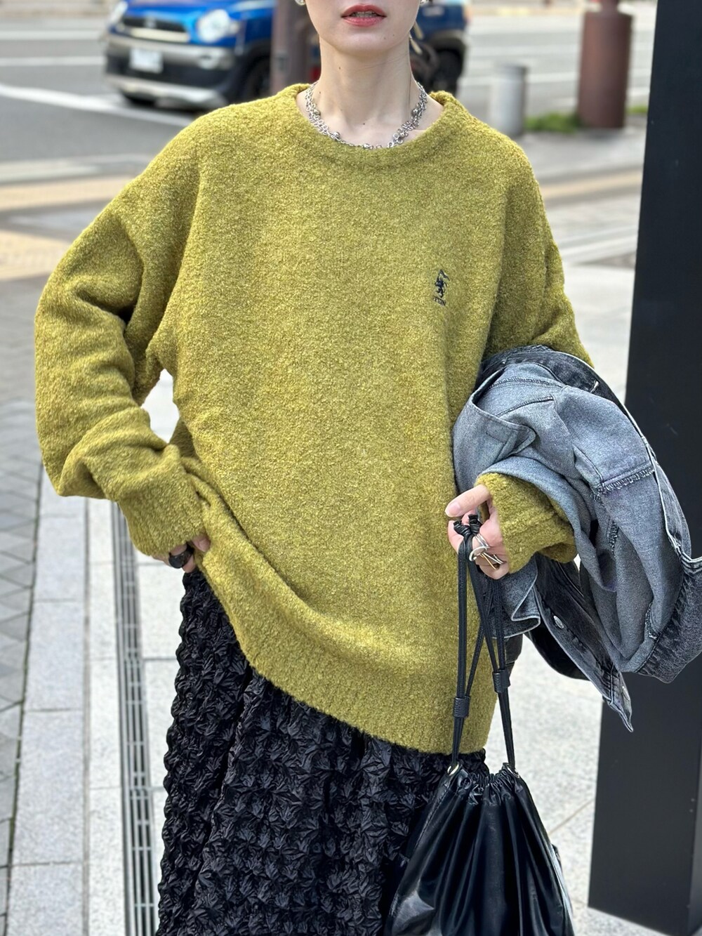 イエロー系のニット/セーター、ブラック系のハンドバッグ、グレー系のスニーカーを着用したレディースの秋コーディネートの2枚目の写真