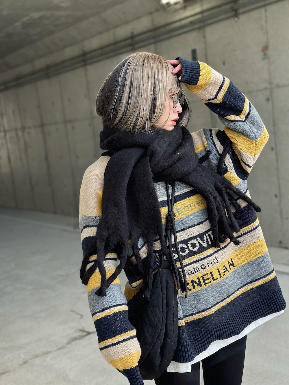 ブルー系のニット/セーター、ブラック系のショルダーバッグ、ブラック系のスニーカーを着用したレディースの冬コーディネートの2枚目の写真