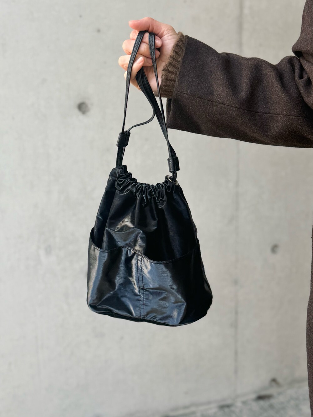 ブラウン系のステンカラーコート、ブラック系のハンドバッグ、ブラック系のその他パンツを着用したレディースの冬コーディネートの5枚目の写真