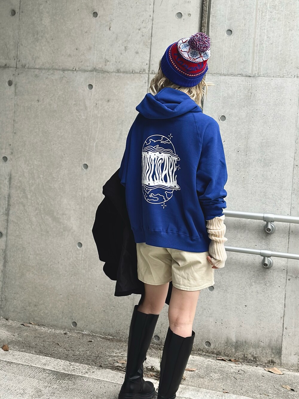 ブラック系のノーカラーコート、ブルー系のパーカー、ホワイト系のその他パンツを着用したレディースの冬コーディネートの5枚目の写真