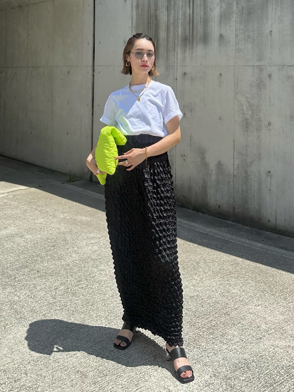 ホワイト系のTシャツ/カットソー、ブラック系のスカート、ブラック系のサンダルを着用したレディースの夏コーディネートの4枚目の写真