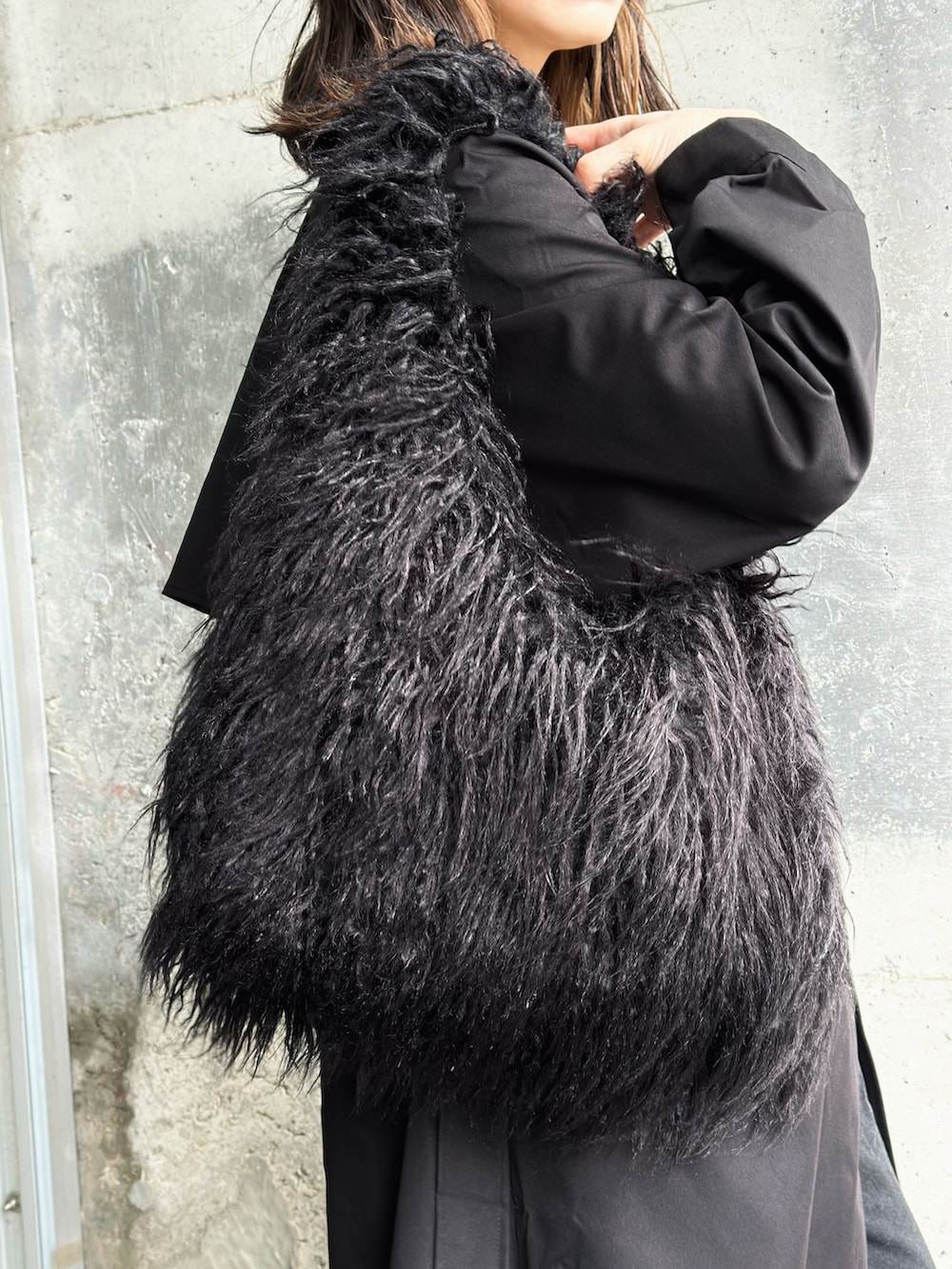 グリーン系のTシャツ/カットソー、ブラック系のトレンチコート、ブラック系のトートバッグを着用したレディースの春コーディネートの3枚目の写真