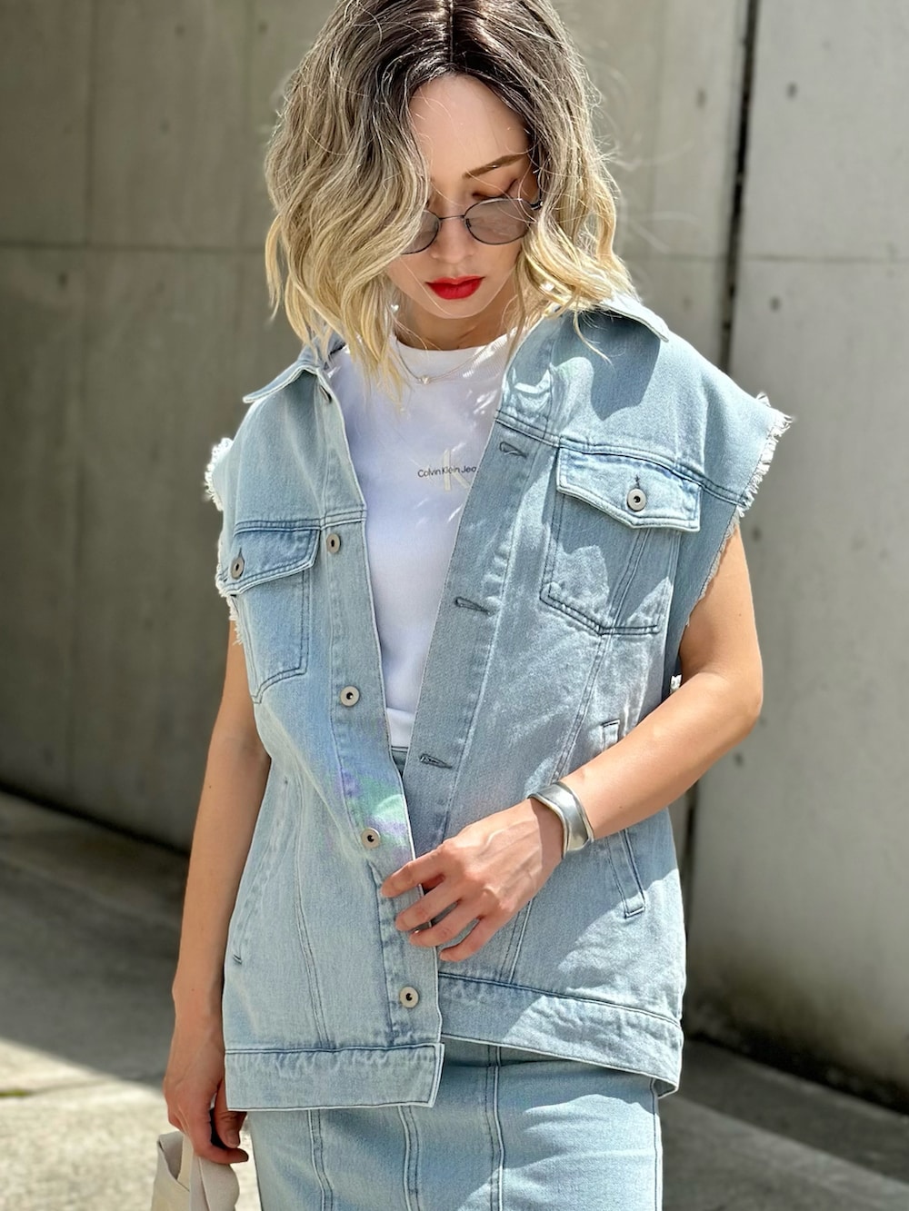 ブルー系のベスト、ブルー系のデニムスカート、ホワイト系のTシャツ/カットソーを着用したレディースの春コーディネートの2枚目の写真